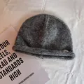 Detailed close-up of grey knit beanie with rolled brim and a small round metal tag - M (55-59cm) / Dark Gray
