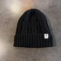 Dettaglio del berretto nero in maglia a trecce con risvolto spesso e logo a stella - Elastico / Nero