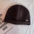 Detailed view of dark brown knitted beanie texture and silver metal brand emblem - M (55-59cm) / Coffee