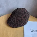 Vista detallada de boina vintage con estampado de leopardo sobre una mesa de madera real - M / Café Negro