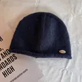 Detail shot of navy blue wool knit beanie featuring a silver metal logo and rolled edge - M (55-59cm) / Navy Blue