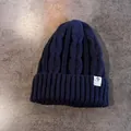Dettaglio del berretto blu scuro a trecce che mostra la trama spessa e l'etichetta a stella - Elastico / Blu navy