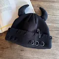 Dettaglio berretto nero con corna di diavolo, effetto usurato, spille e anelli di metallo - Nero