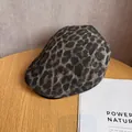 Detalle de la gorra con estampado de leopardo sobre una mesa de madera con revista - M / Gris Negro Caqui