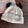 Dettaglio del berretto in maglia bianca con corna di demone e spilla da balia punk - Bianco Con Corna Nere
