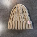 Dettaglio della trama a trecce e dell'etichetta in pelle rosa del berretto invernale - Elastico / Cachi