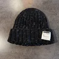 Dettaglio di berretto in maglia melange bianco e nero con etichetta con lettera cucita - Nero / Elastico