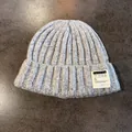Close-up of thick grey knit beanie featuring a white letter patch and ribbed texture - Light Gray / Elastic