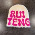 Detail of soft cream faux mink beanie featuring a vibrant pink embroidered letter logo - M / Beige