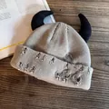 Detail of khaki distressed knit beanie featuring punk horns and silver metal pin accents - Khaki