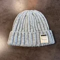 Detailed close-up of light blue knit beanie showing thick ribbed texture and woven label - Blue / Elastic