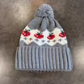 Dettaglio del cappello in maglia grigia con motivi a fragola e pompon morbido - Grigio
