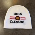 Close-up of white knit beanie with black jacquard lettering and cartoon robot character - White