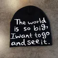 Close-up of black knitted beanie with white jacquard motto text on flat gray background - Black