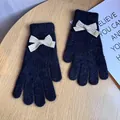 Dettaglio di guanti in maglia neri pelosi con fiocco beige e ciondolo inciso Baby - Nero