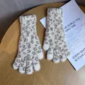 Nahaufnahme von Plüschhandschuhen mit Leopardenmuster auf einem Holztisch - Beige
