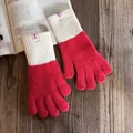 Detail von rot-weißen Strickhandschuhen mit Rippbündchen auf rustikalem Holztisch - Rot