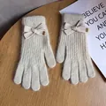 Close-up of beige knitted gloves with cute bow tie decoration and soft fuzzy texture - Khaki