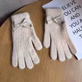 Detail of cream white knit gloves featuring a cute 3D bow and Baby metal tag - Beige