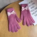 Close-up of rose pink knit gloves featuring a light pink bow and metallic Baby tag - Rose Red