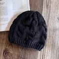 Dettaglio di un berretto nero a maglia intrecciata in lana spessa su tavolo di legno - Nero