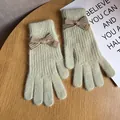 Close-up of green knit gloves with a brown bow and baby engraved metal buckle - Pale Green