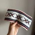 Detail view of ethnic jacquard knit headband with blue and red geometric diamond patterns - Beige