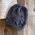 Dettaglio macro del berretto grigio antracite a treccia su una superficie in legno caldo - grigio scuro
