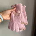 Close-up of pink knit winter gloves featuring plush texture and cute bow details - Pink