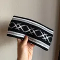 Detailed close-up of ethnic jacquard knit headband showing warm grey diamond pattern - Black