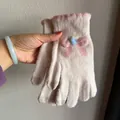 Detail of pink knitted touchscreen gloves with bow decoration and warm winter texture - Beige