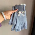 Close-up of light blue knitted glove with plush bow and white scalloped edge detail - Blue