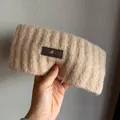 Detail of beige ribbed knit headband featuring a premium leather logo patch and soft texture - Khaki