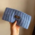 Detailed knit texture and brown leather logo tag on a blue winter headband - Blue