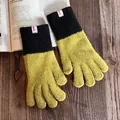 Nahaufnahme der farblich abgesetzten Strickhandschuhe mit weicher Textur auf Holzgrund - Grün