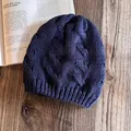 Dettaglio di un berretto in maglia a trecce blu navy con motivi a treccia su legno - Blu navy