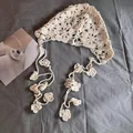 Detailansicht des beigen Häkel-Bandanas mit Lochmuster-Blumen und dekorativen Quasten - M (55-59cm) / Beige