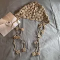 Detail eines beige gehäkelten Kopftuchs mit Blumenstickerei und langen Quasten - M (55-59cm) / Khaki