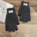 Detail view of dark grey winter knitted touchscreen gloves with ribbed cuffs on wooden table - One Size / Gray
