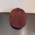 Detail view of stitched suede fabric on dark brown newsboy cap with top decorative button - M (56-58cm) / Burgundy