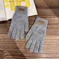 Detail of dark grey knit gloves with brown leather fashion tag and ribbed warm cuffs - One Size / Gray