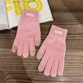 Close-up of pink knit touchscreen gloves with fashion label on rustic wooden surface - One Size / Pink