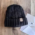 Close-up of black cable knit beanie with leather patch on textured wood background - M (55-59cm) / Black