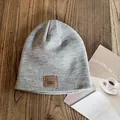 Close-up of grey knit beanie with premium brown leather label on wooden table - M / Gray