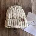 Close-up of beige cable knit beanie with warm fleece lining and leather patch on wood - M (55-59cm) / Beige