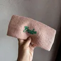 Close-up of pink knitted headband featuring green Boston EST. 1987 embroidery detail - Pink