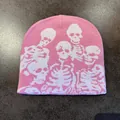 Detail shot of a pink knitted beanie featuring white skull graphic patterns - M / Pink