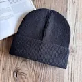 Gros plan du bonnet en maille côtelée noire avec bord replié sur bois clair - M / Noir