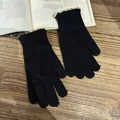 Details von schwarzen Strickhandschuhen mit rosa-grüner Wellenbordüre auf Buch - Schwarz