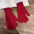 Detailaufnahme roter Strickhandschuhe mit blau-weißem Wellenrand auf Holzgrund - Rot